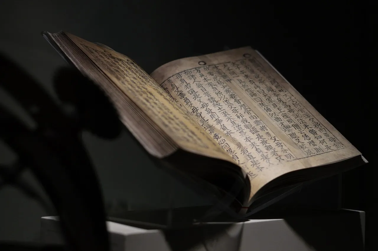 An old book of Chinese text lying open under a spotlight