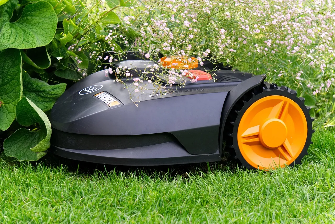 A robot lawn mower parked on cut grass beside a flower border