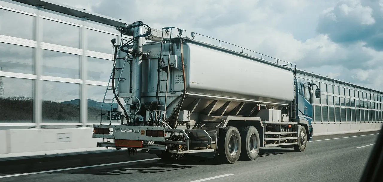 A tanker lorry on a multi-lane highway, seen alongside a concrete barrier.