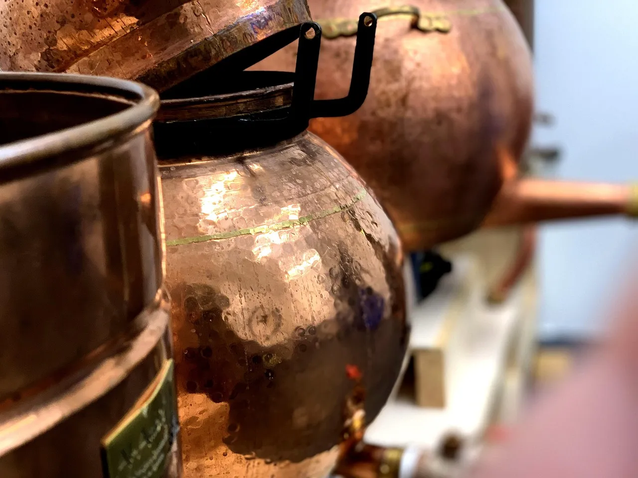 A copper pot still, its rounded vessels and condenser pipe catching the light