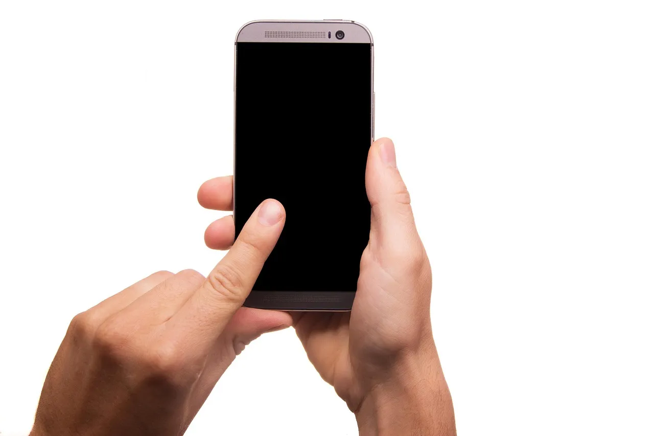 Illustrative: two hands holding a smartphone with a blank screen, thumb poised over it.
