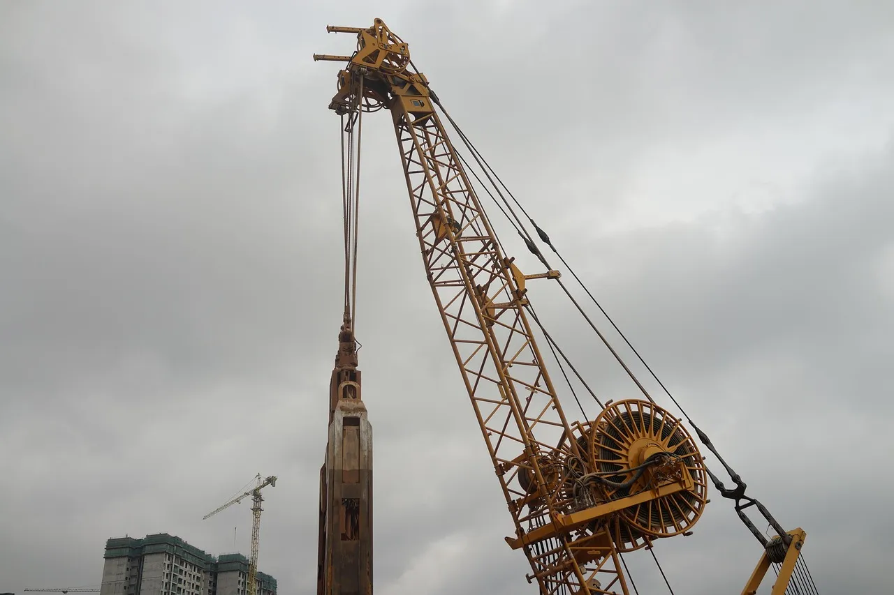 A piling rig and tower crane on an Asian construction site, the stage at which an announced project becomes a real one
