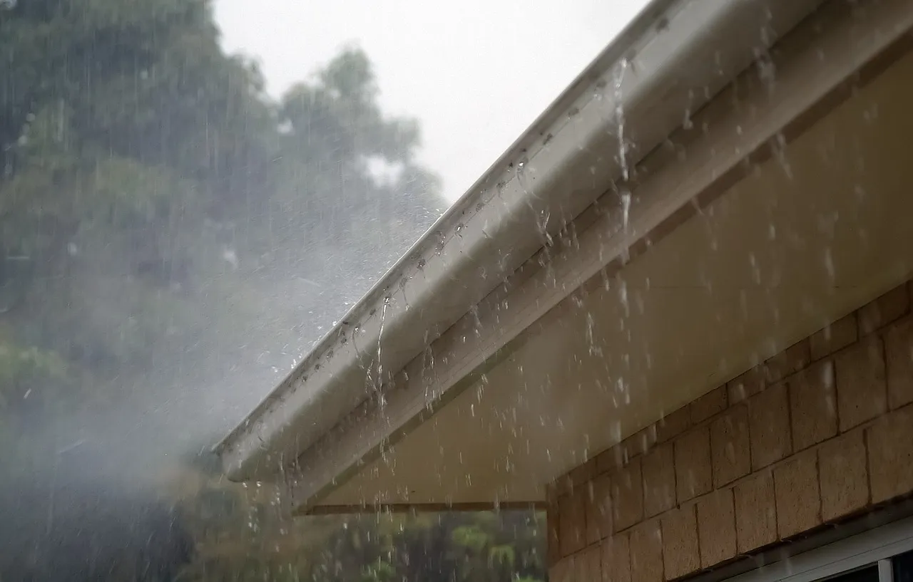 Rain running off the edge of a roof gutter in a heavy shower