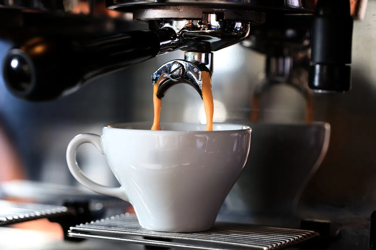 Espresso pouring from a machine spout into a white cup