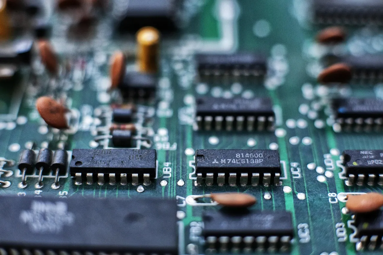 A macro photograph of a green circuit board, rows of small black integrated circuits and resistors in sharp focus across the middle and blurring towards the edges.