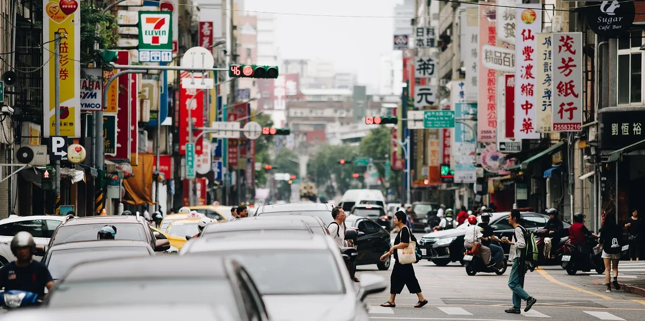 A busy shopping street in Taipei with signboards and scooters