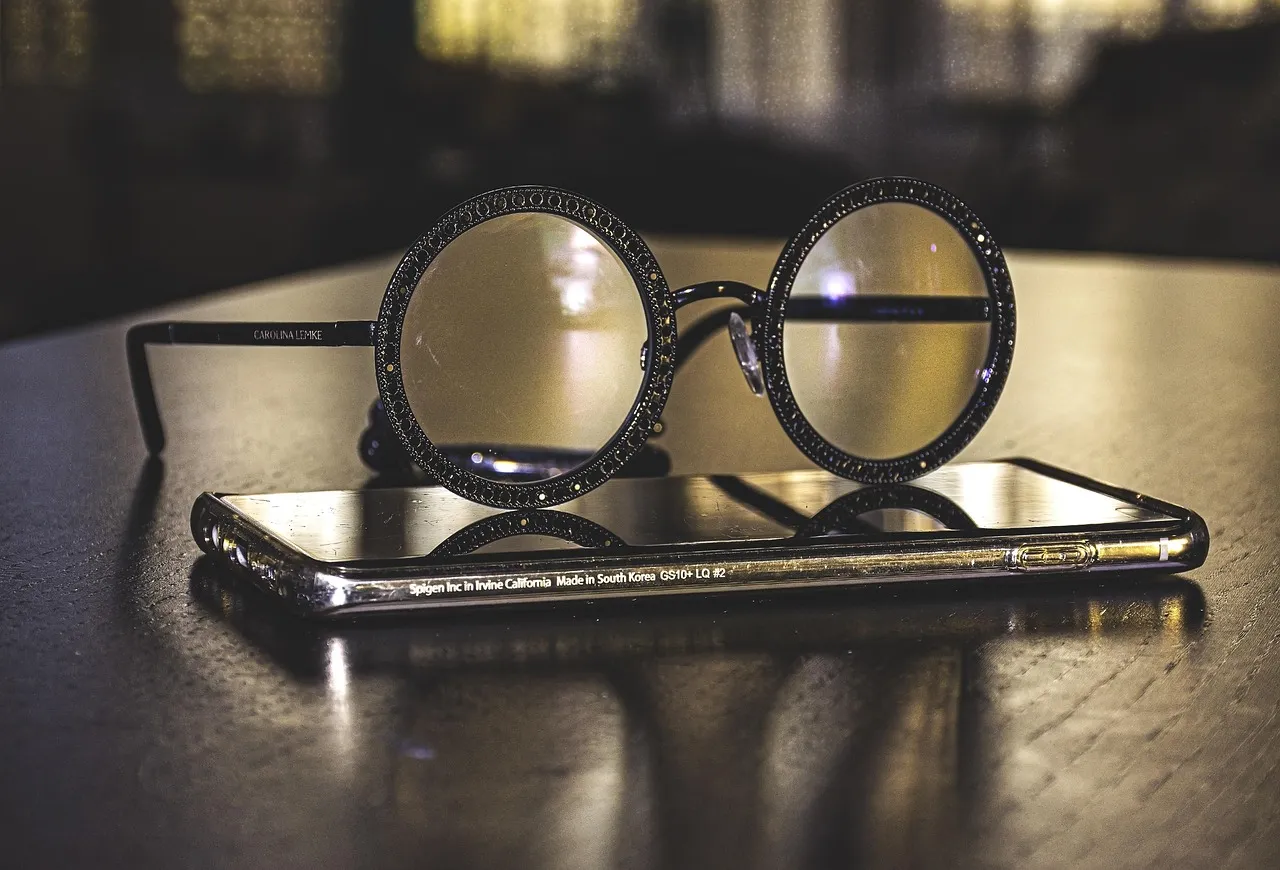 A pair of glasses resting on a smartphone, the two devices whose recording notice the article compares