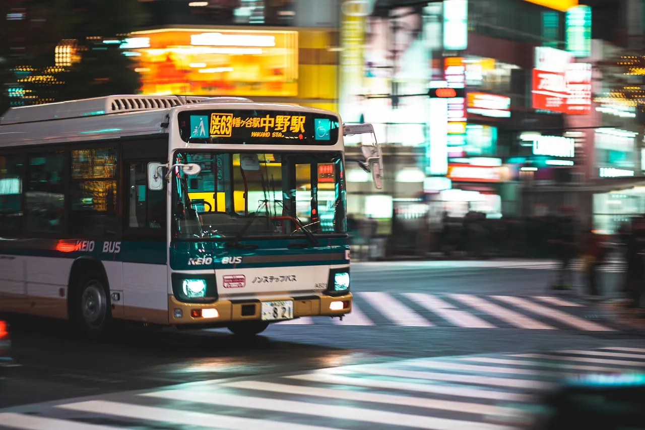 A city bus crossing an illuminated Tokyo intersection at night