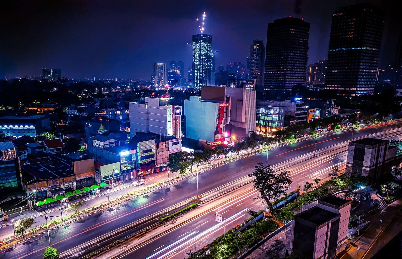Jakarta at night, with traffic light trails along a main road and towers behind