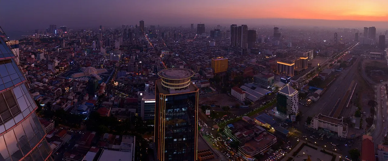 The Phnom Penh skyline at dusk, towers lit against a violet sky