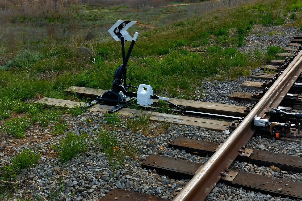 A manual railway points lever beside a track, its arrow indicator showing which way the junction is set