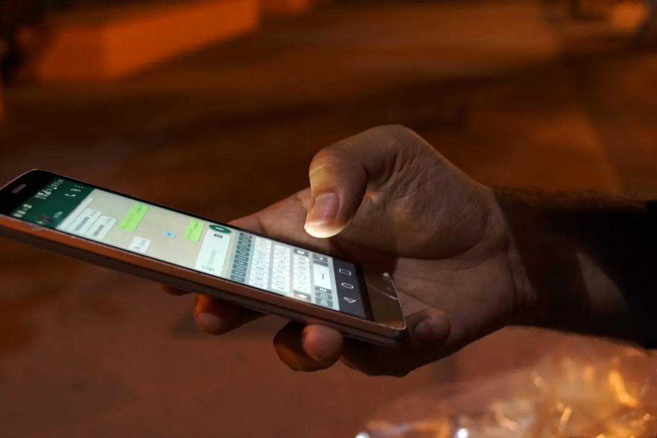 A hand holding a smartphone open to a chat thread in dim evening light