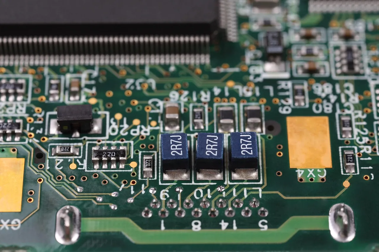 Close-up of a green printed circuit board showing surface-mounted components, solder pads and a connector edge