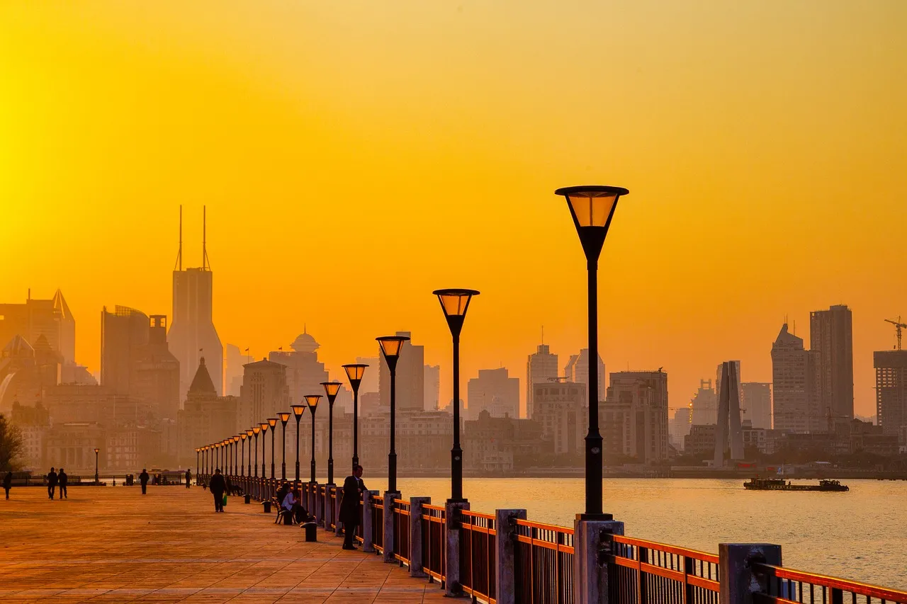 The Shanghai waterfront at sunset, lamp posts along the promenade with the Pudong skyline behind.