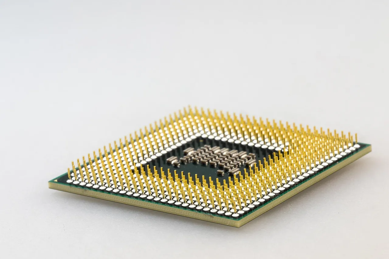 A computer processor package seen from above, gold pins on a green substrate