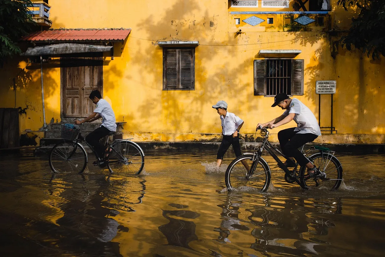 People cycling and walking through a flooded street