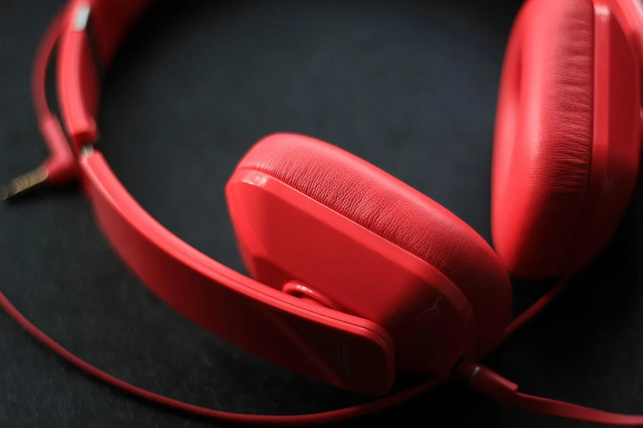 A pair of red over-ear headphones resting on a dark surface