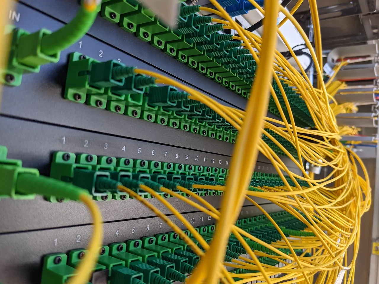 A fibre patch panel with rows of green connectors and yellow patch leads, illustrating a report on a mass exploitation campaign against VMware vCenter.
