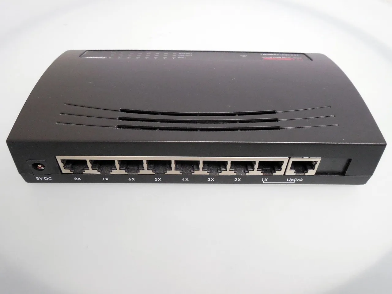 A black eight-port network switch photographed against a white background, its numbered ethernet sockets facing the camera.