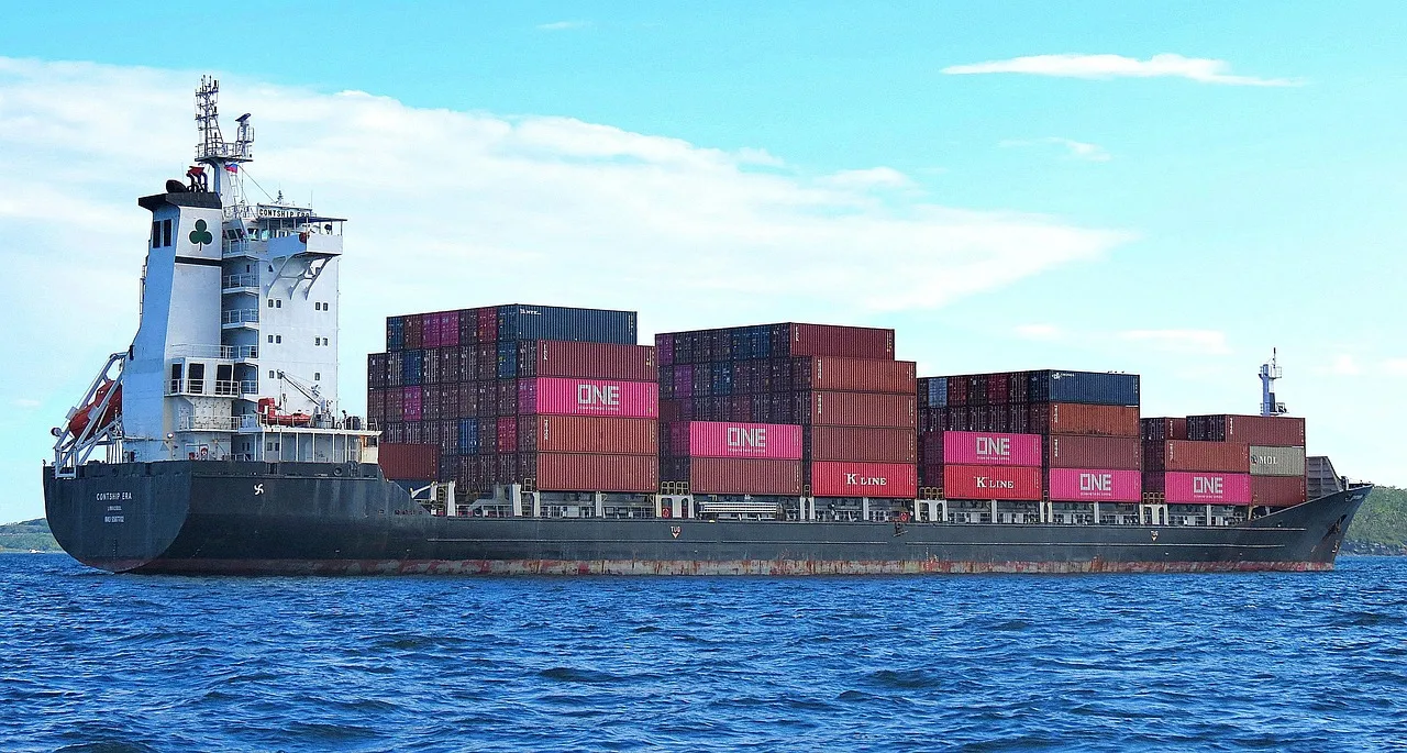 A container ship under way in open water, its deck stacked with boxes belonging to several different operators — illustrative of the merchant fleet a maritime nuclear framework would have to govern.