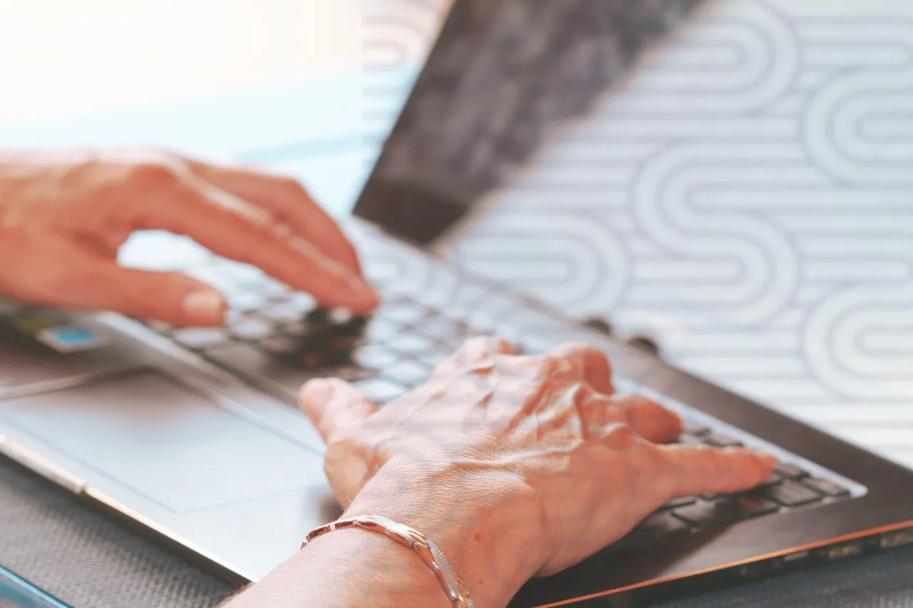 Two hands typing on a laptop keyboard