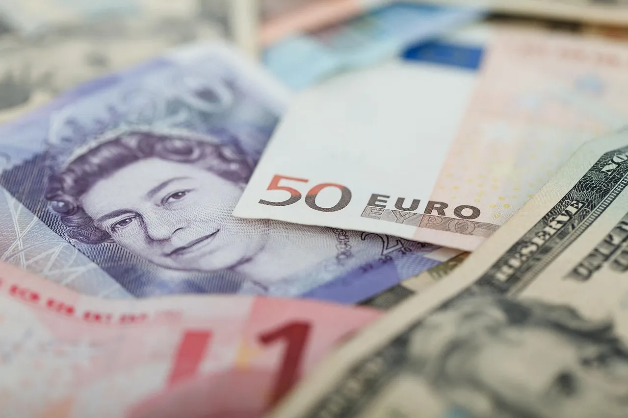 Banknotes of several different currencies overlapping in a loose pile, including a fifty-euro note and a US dollar bill