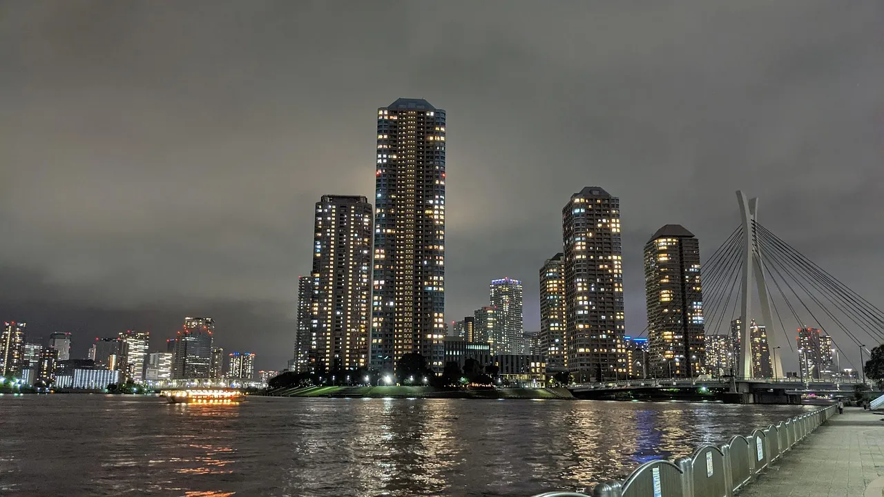 Tokyo waterfront towers lit up at night, reflected in the water below.