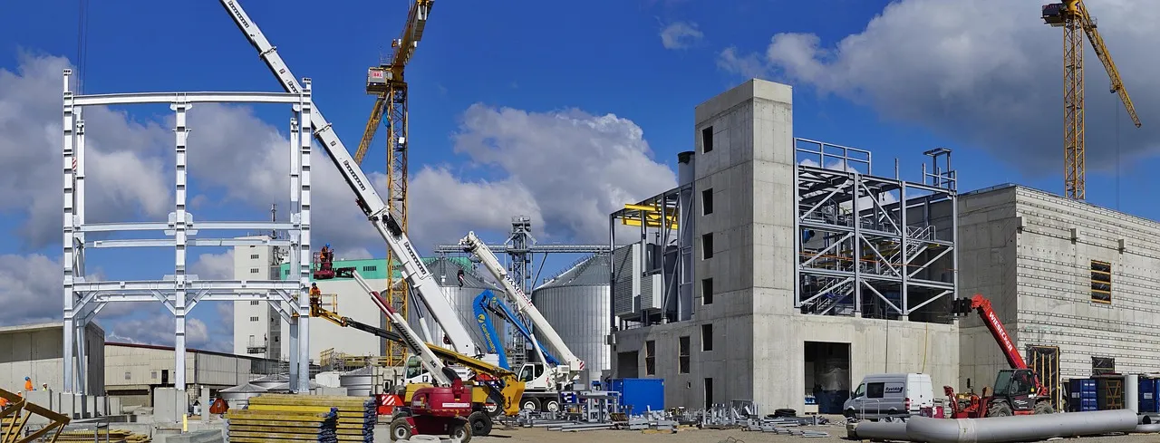 A large industrial building part-built, steel framing and a bare concrete core standing between two tower cranes — illustrative of the phase-one stage the Terafab commitment covers.