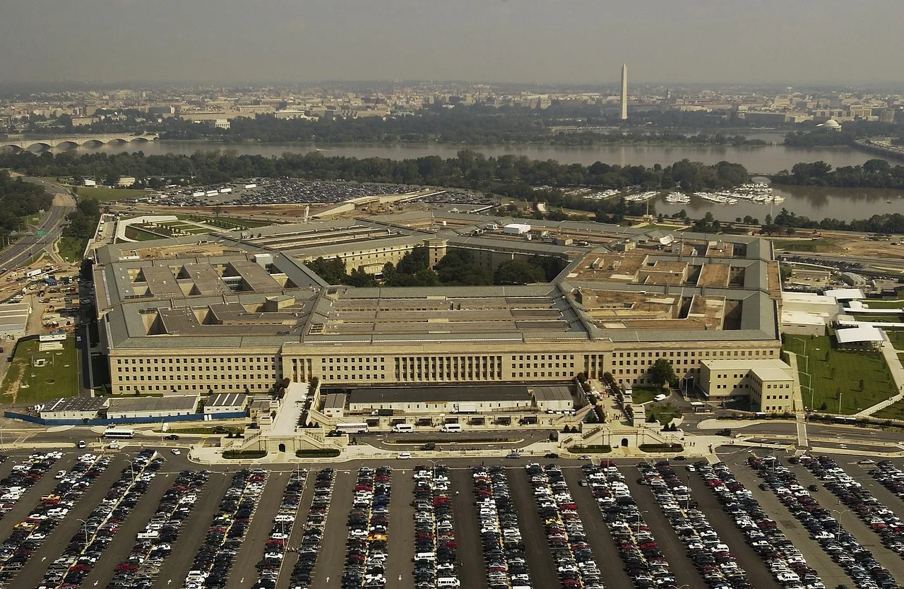 An aerial view of the Pentagon and its car parks, with the Potomac and the Washington Monument behind it