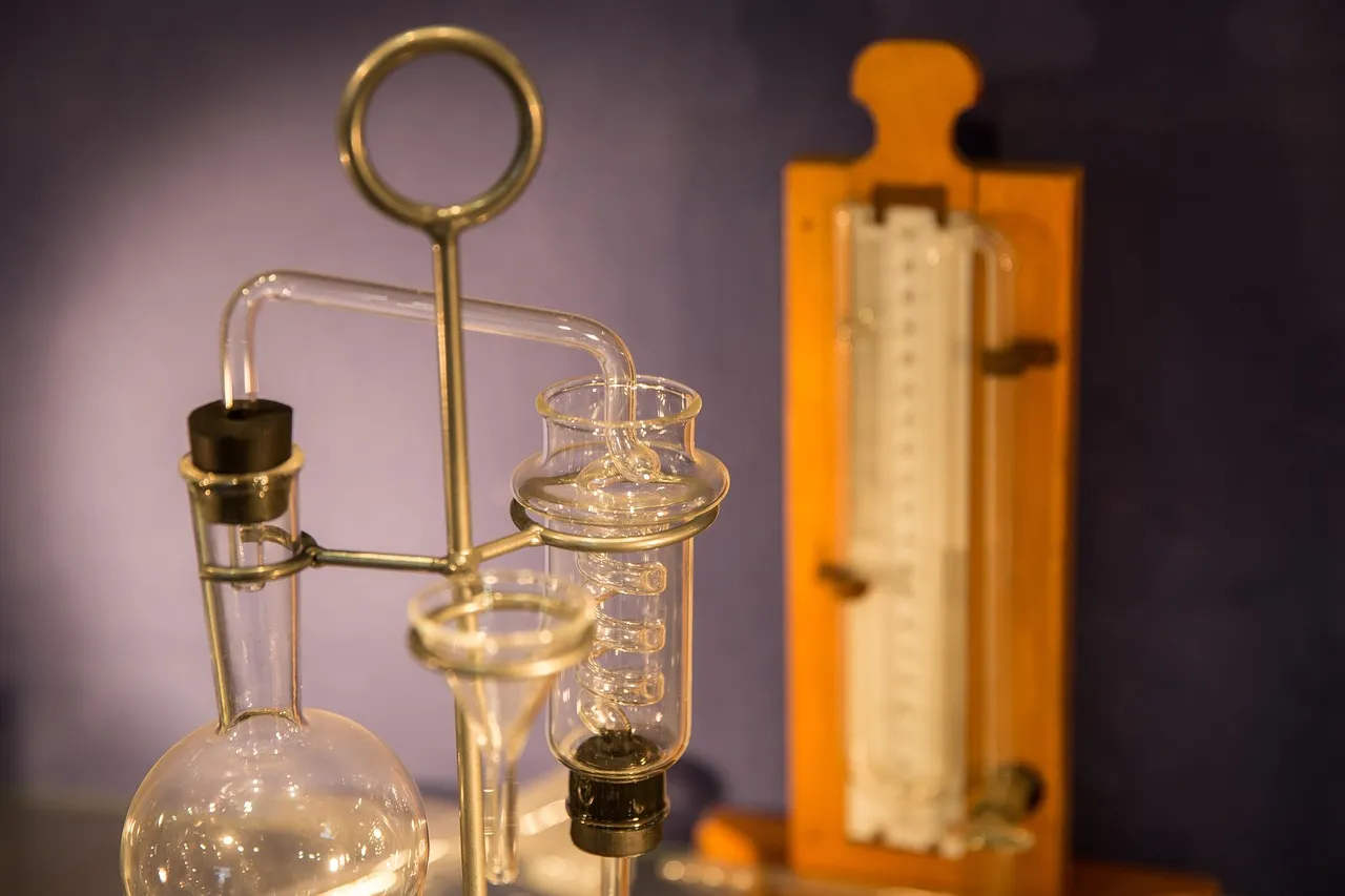 Antique glass laboratory apparatus on a metal stand, lit in warm amber light.