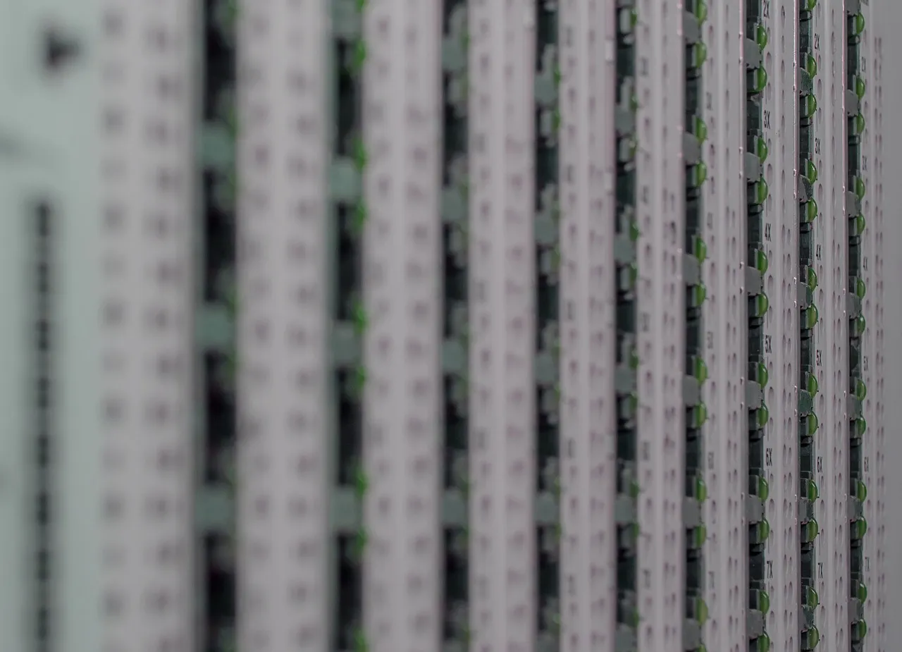 A close-up of stacked network switch ports with green link lights, receding out of focus