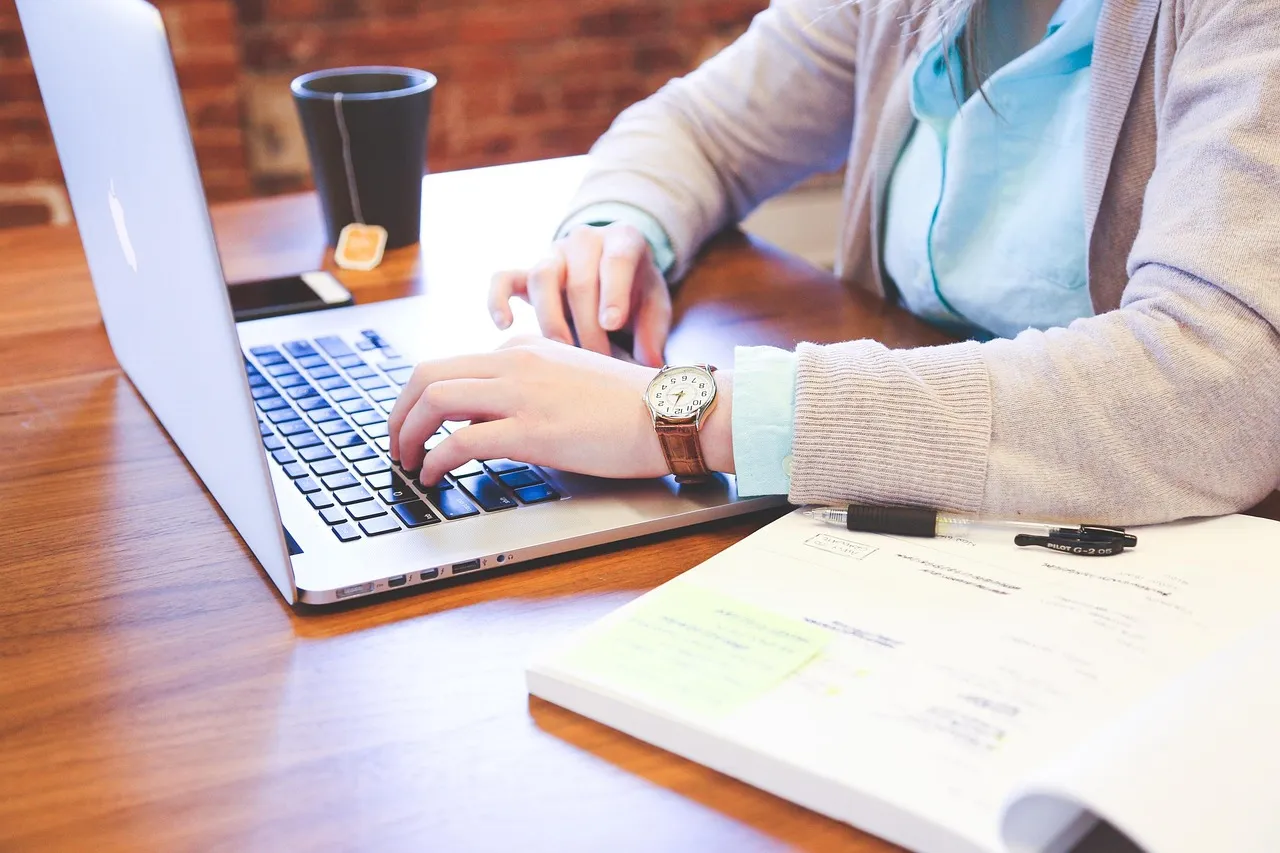 Someone typing on a laptop beside handwritten notes, the setting in which a chat mode is chosen without much thought