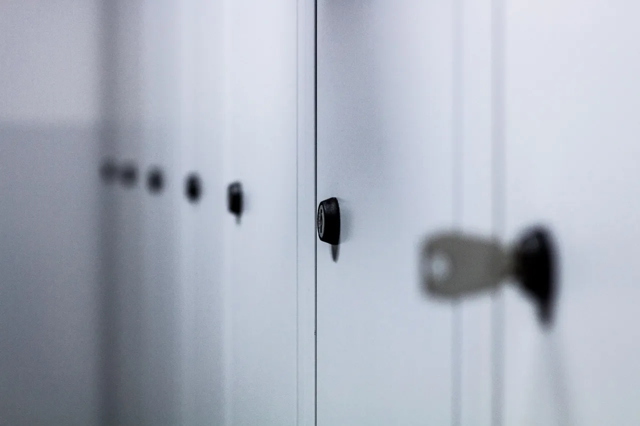 A close-up of a row of pale locker doors, each fitted with its own separate lock