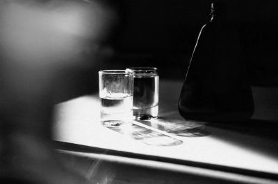 A stark black and white image capturing glasses and shadows on a table.