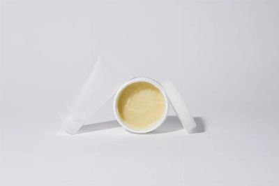 Studio shot of white plastic containers with yellow cream product on a white background.